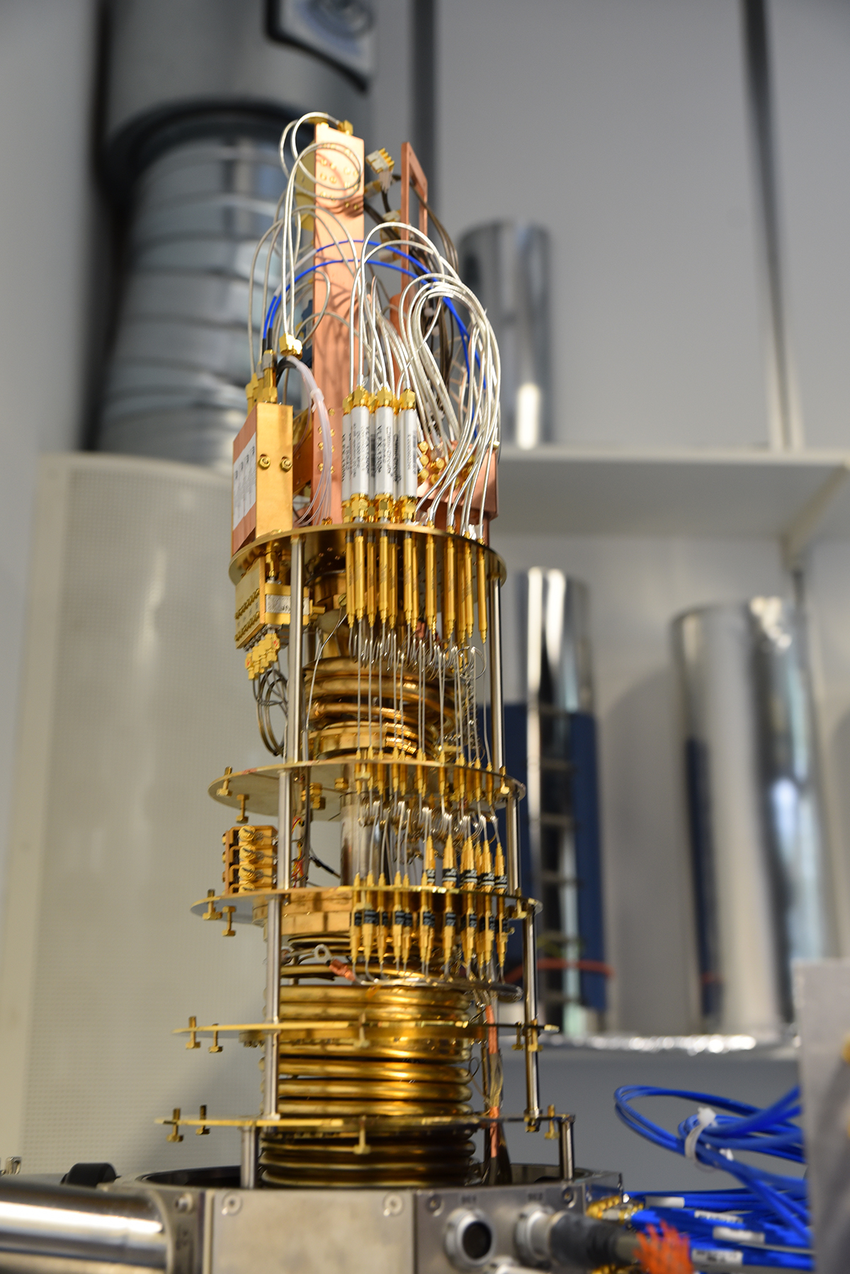 A quantum computer, a tower-like, brass colored shining structure with cables. 